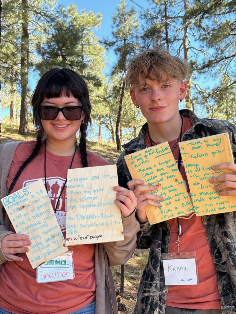 Anytown alumni smiling and holding their goal boards at camp