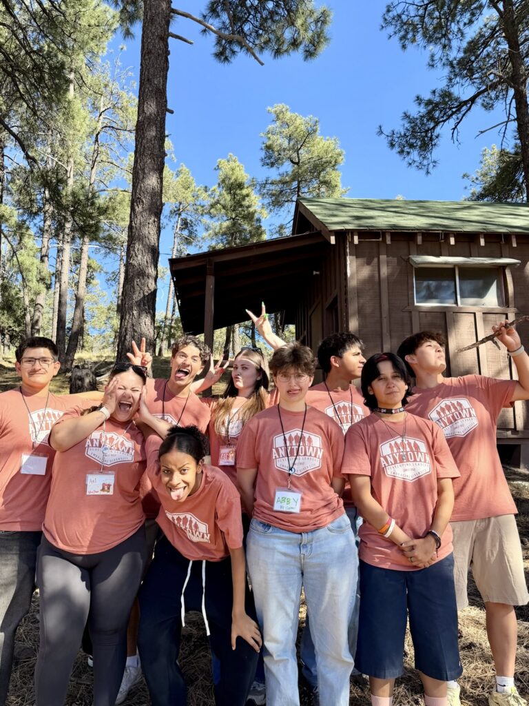 Anytown counselors goofing around in front of a camp cabin