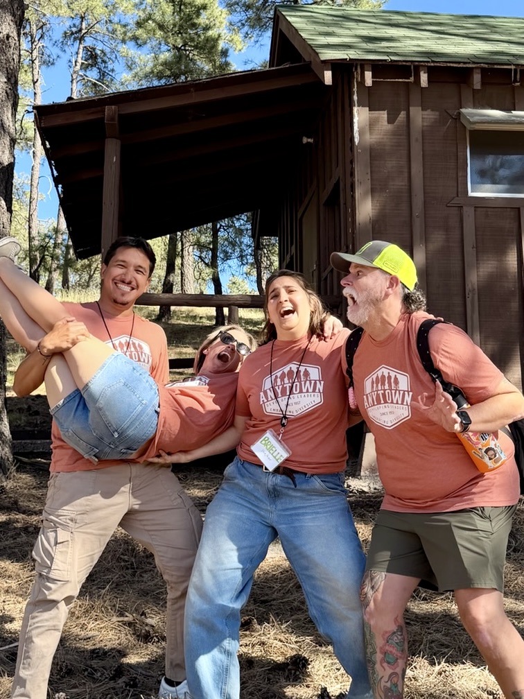 Anytown camp directors laughing together in front of a camp cabin