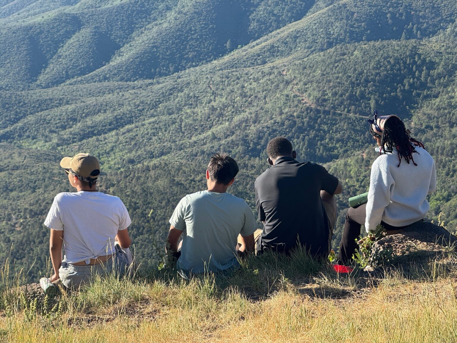 Delegates sitting together on a ridge overlooking the mountains