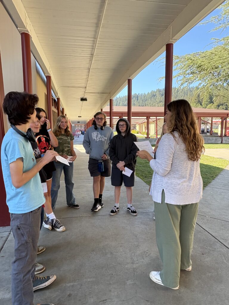 An Anytown facilitator leading a conversation with a group of students in a school hallway